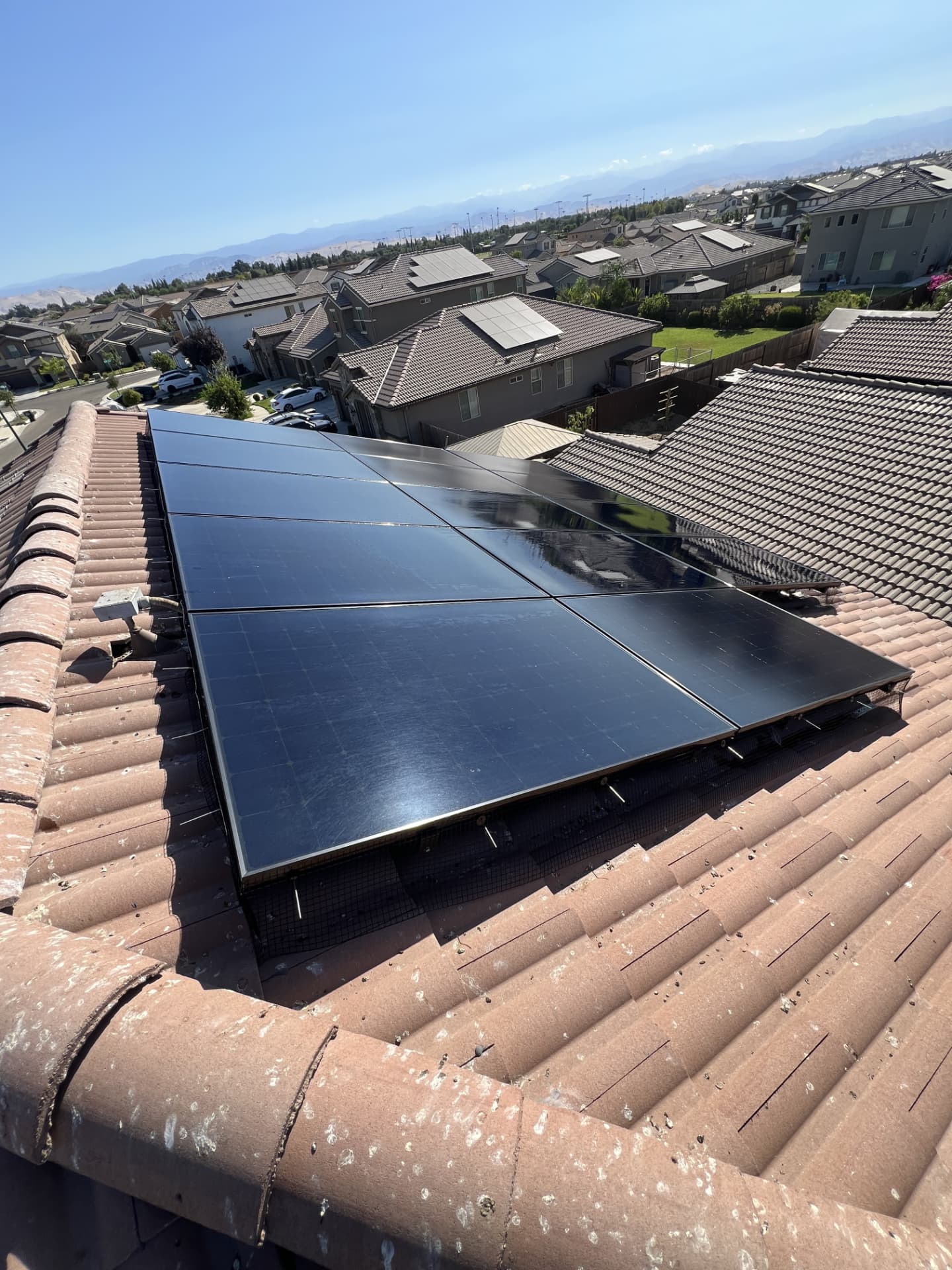 Solar array with bird guard mesh installed on a tile roof overlooking the Central Valley