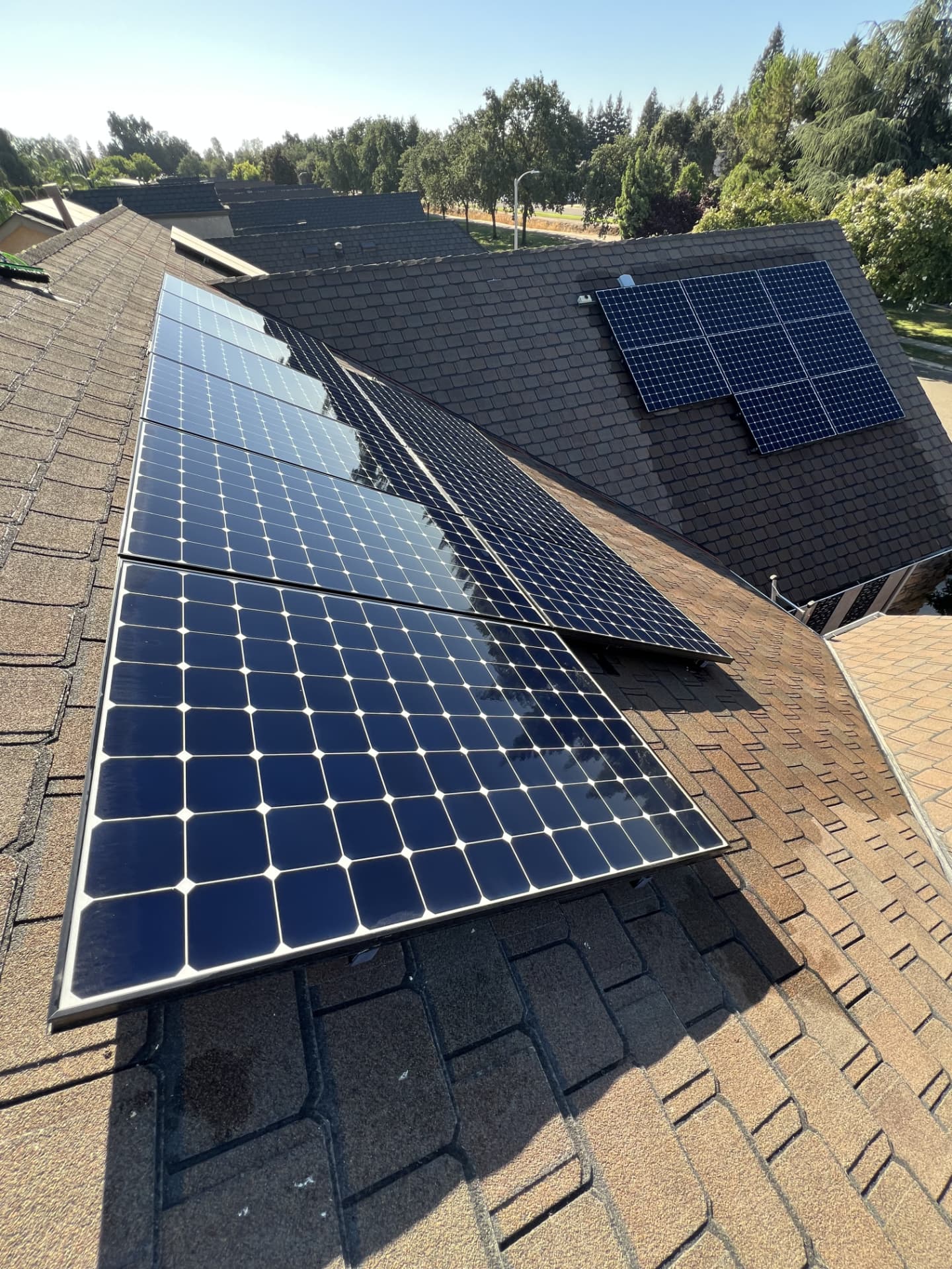 Two freshly cleaned solar arrays on a residential shingle roof