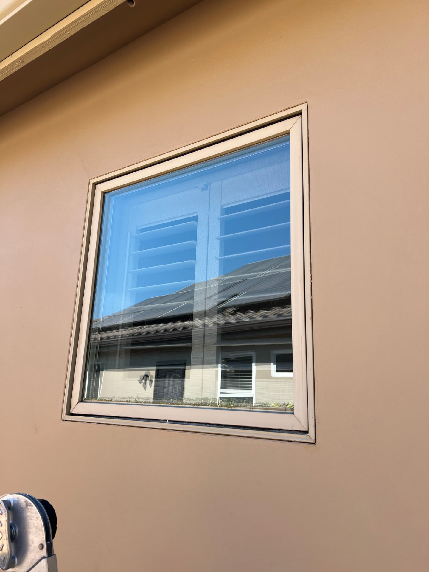 Streak-free cleaned window reflecting a blue sky and rooftop solar panels