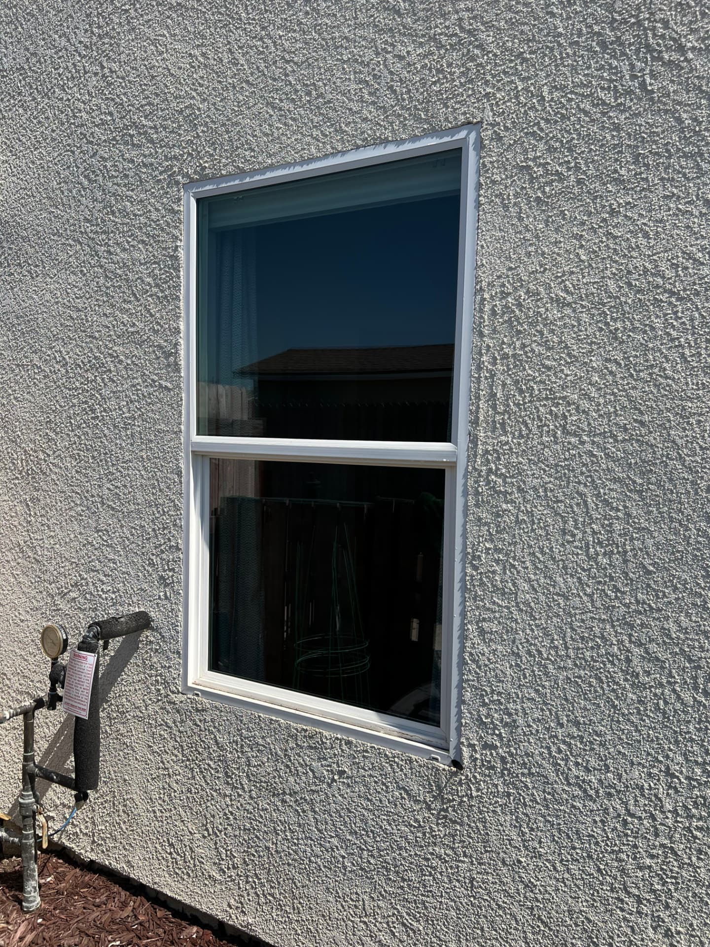 Streak-free cleaned exterior window on a gray stucco wall