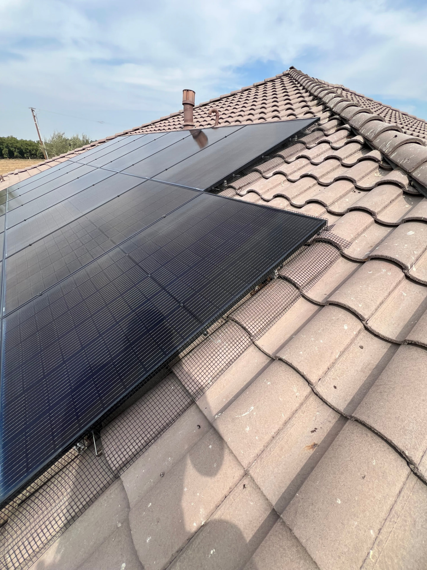 Bird guard mesh wrapping the corner of a solar array on a tile roof