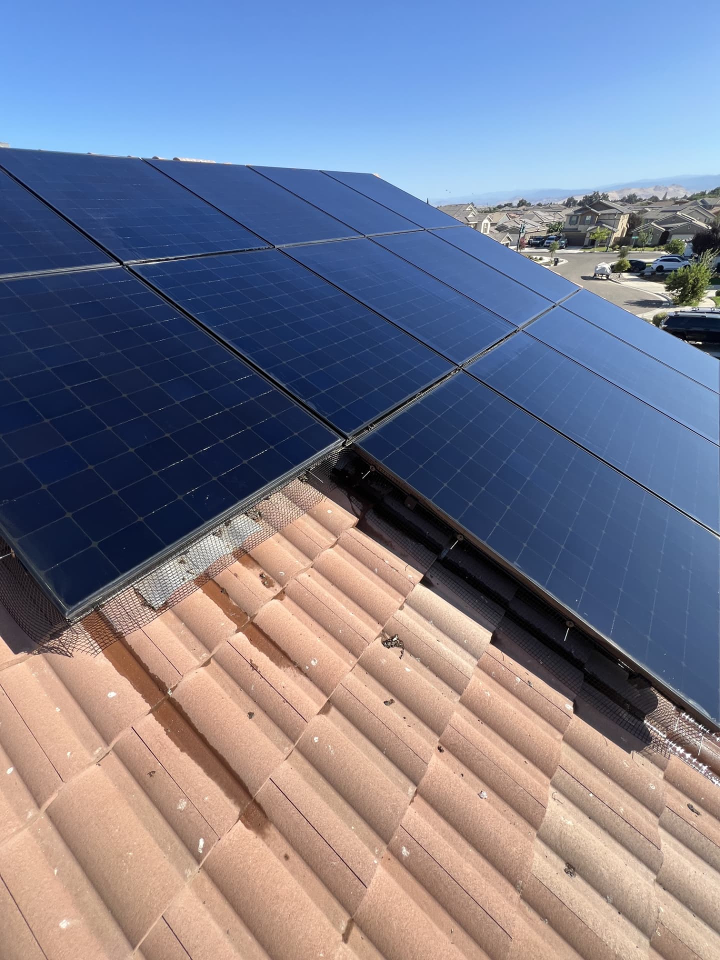 Bird guard mesh installed beneath large solar panels on a tile roof