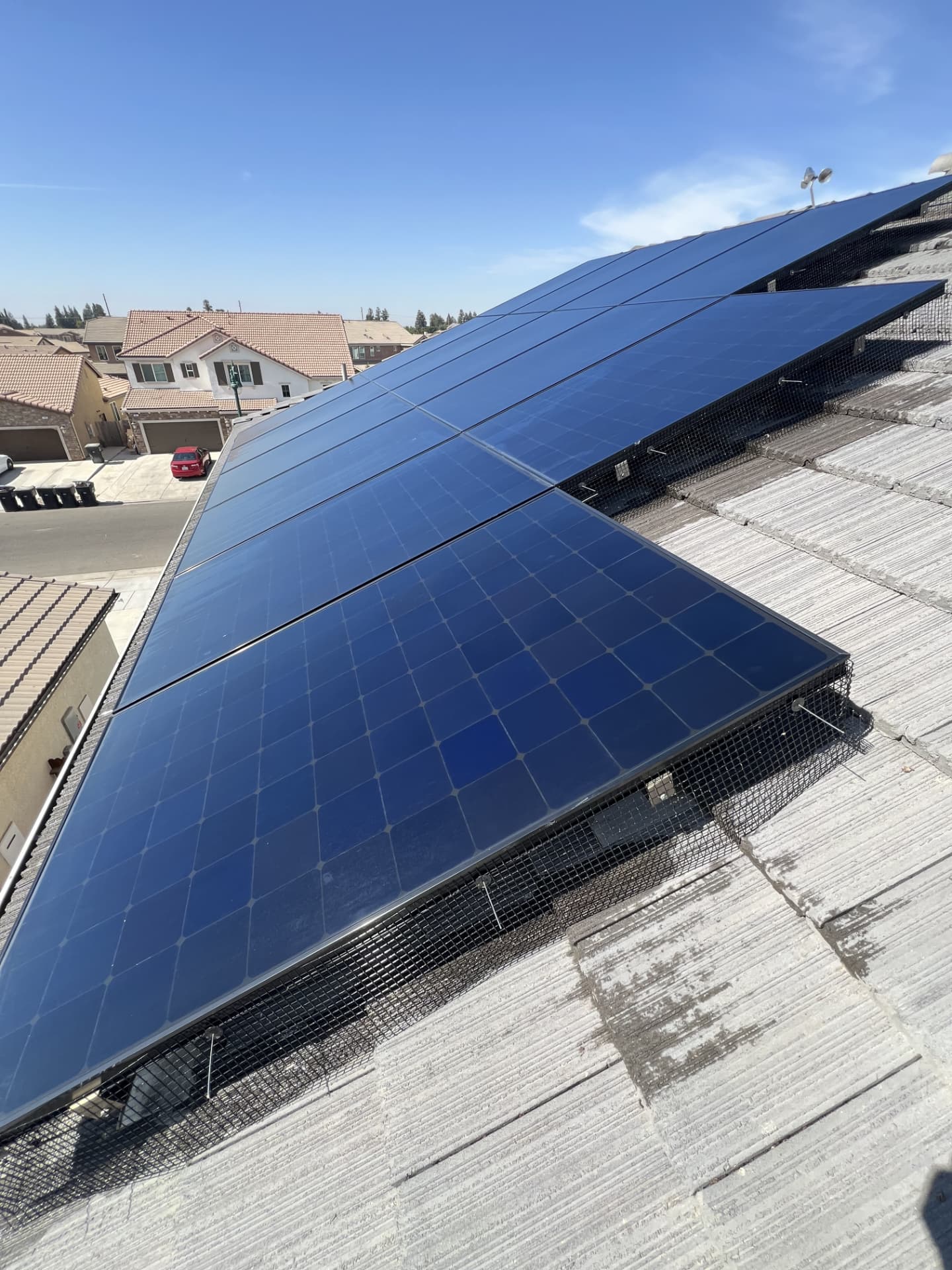 Long row of solar panels with bird guard mesh installed along the entire lower edge