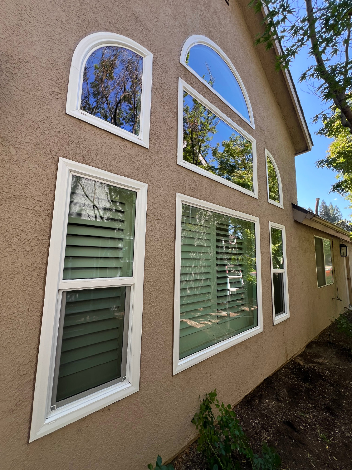 Wall of arched and rectangular windows cleaned spotless on a stucco home