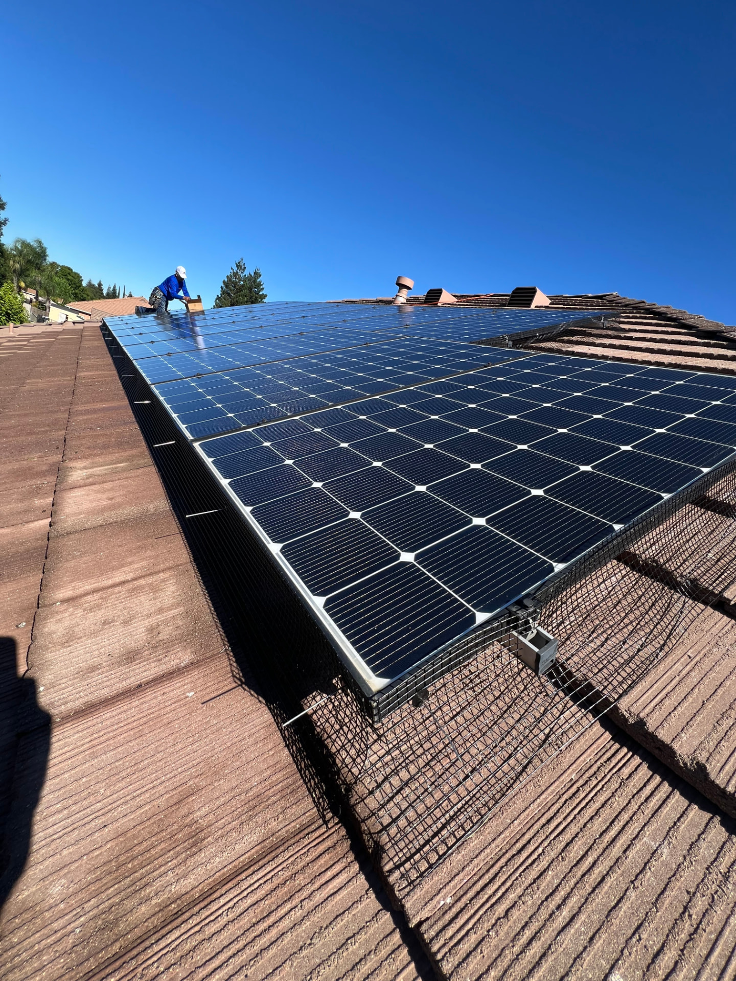 Technician cleaning a large rooftop solar array with deionized water