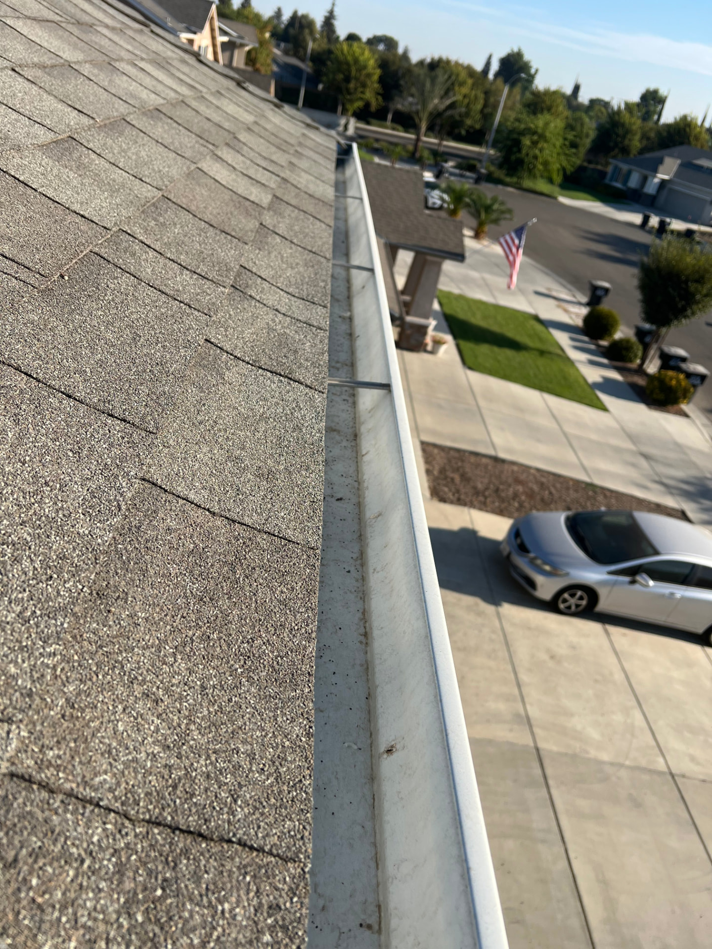 Clean, debris-free rain gutter running along a shingle roof edge